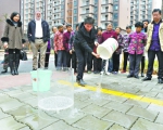 现场一位居民将一大桶水泼洒在小区路面上，2秒钟，水全部被“喝干”，路面变得干爽如初。记者刘斌 摄 - 新浪湖北