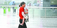右图：受“天鸽”强台风影响，昨天下午4时，我市突降暴雨，在汉口火车站广场上，一妇女抱着孩子赤脚冒雨赶路（记者杨涛 摄） - 新浪湖北