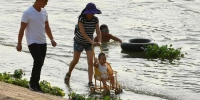 在汉阳晴川桥下，一位女士推着童车在汉江亲水平台上散步，享受清凉的江水。记者金思柳 摄 - 新浪湖北