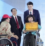 10月13日，中国残奥委主席、中国代表团团长张海迪（右前）展示印尼残奥委会主席森尼·马尔伯恩赠送的礼物 - 残疾人联合会