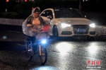 资料图：一名女子驾驶电动车行驶在雨中。中新社记者 陈骥旻 摄 - 新浪湖北