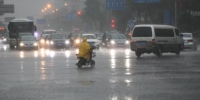 资料图：一名市民穿着雨衣骑车出行。中新社记者 贾天勇 摄 - 新浪湖北