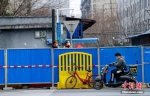 3月6日，武汉汉阳鹦鹉大道，两位市民在墙内往外张望，一位市民骑车从墙外经过。 中新社记者 张畅 摄 - 新浪湖北