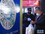 4月8日凌晨，值守在武昌火车站的工作人员协助进站乘客扫描健康码。 新华社记者 李贺 摄 - 新浪湖北