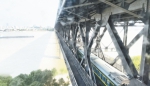 透过汉阳桥头堡内的窗户，可以看到火车驶过长江大桥。 - Hb.Chinanews.Com