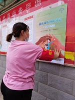 图为志愿者在社区宣传栏张贴残疾预防宣传海报 - 残疾人联合会